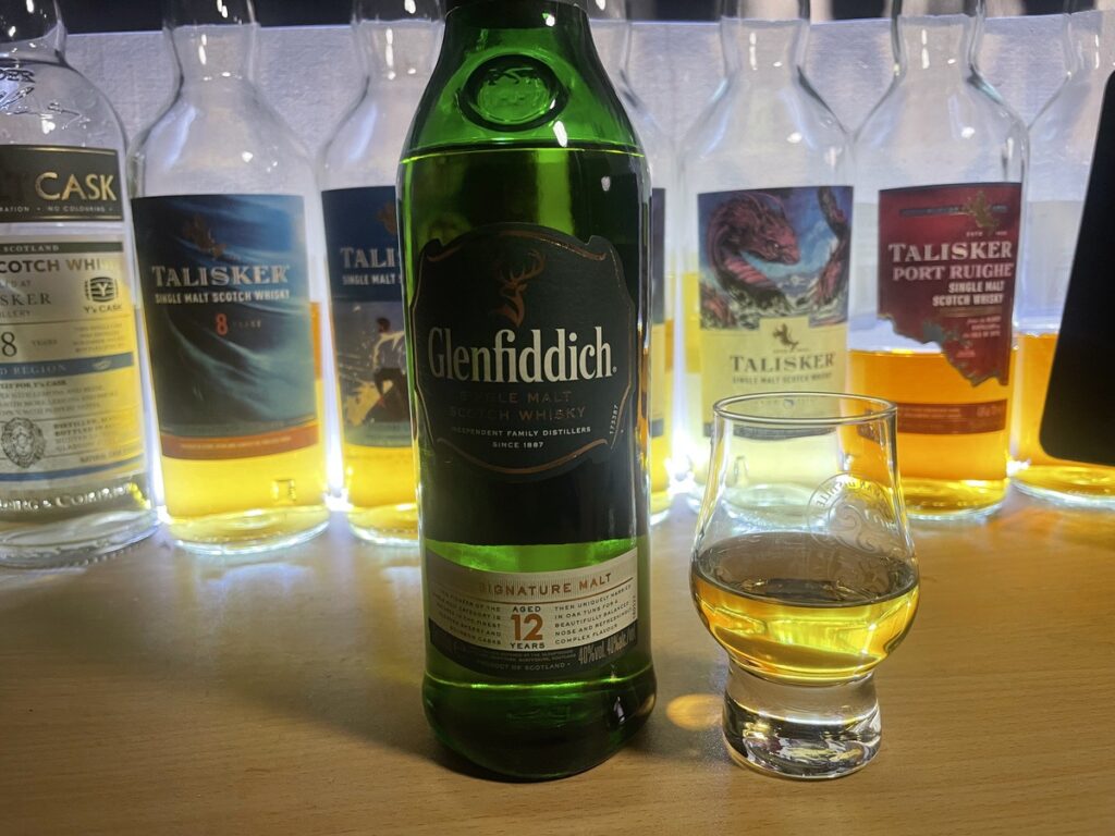 机に置かれたGlenfiddich12年のボトルと注がれたテイスティンググラスの写真