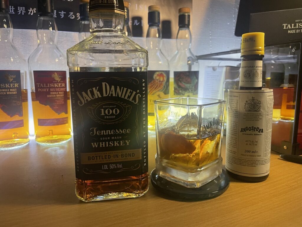 デスクに置かれたジャックダニエルボトルドインボンドのボトルとそれで作ったオールドファッションドの写真