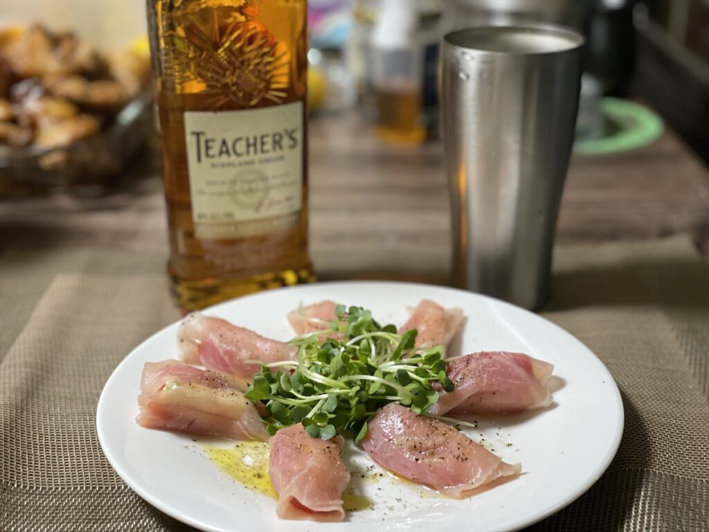 テーブルに置かれたティーチャーズのハイボールと特製ブラックペッパー生ハムチーズの写真